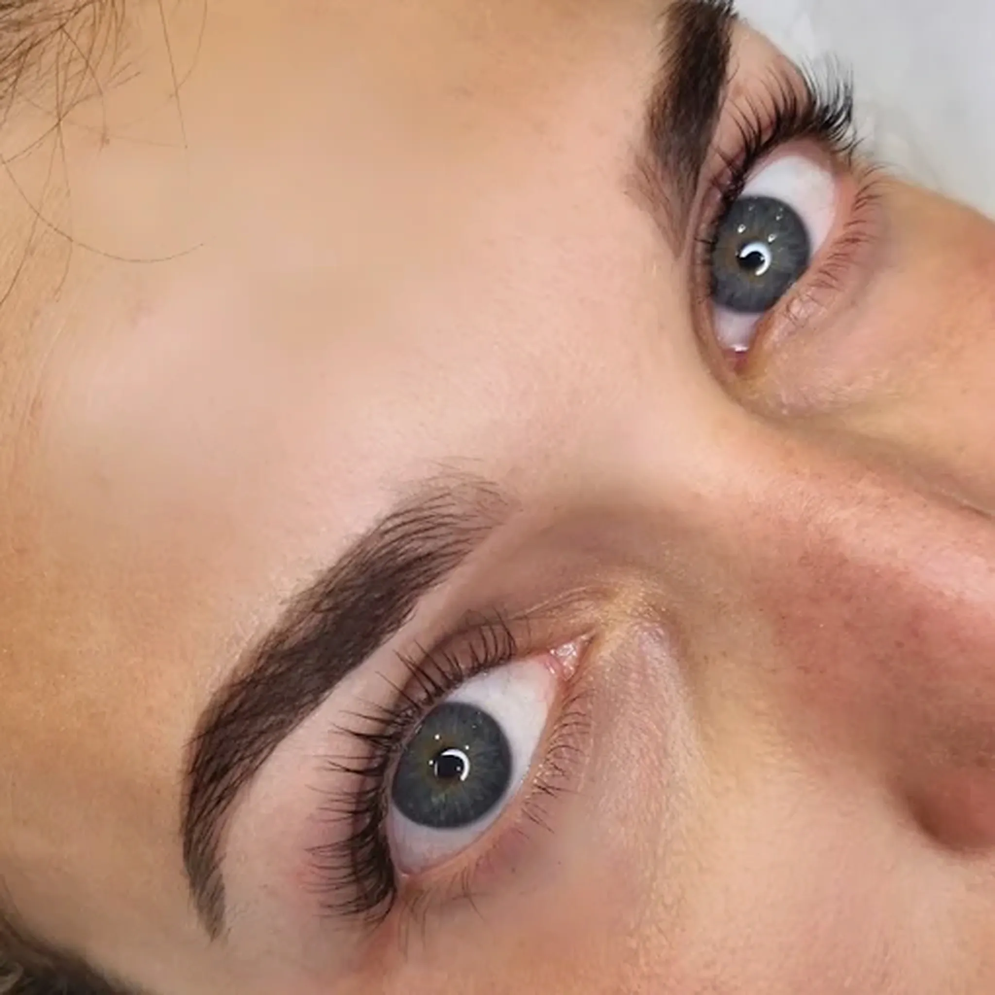Regard aux yeux clairs après rehaussement de cils et mise en forme des sourcils.